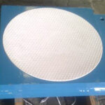 Close-up of the dimpled, low-friction sliding surface of a spherical bearing, designed to allow for rotational movement under heavy loads.