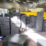 A stack of newly manufactured, solid black elastomeric bearing pads.