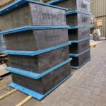 Large, steel-laminated elastomeric bearings stored on industrial shelving.