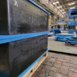 A close-up view of a large, heavy-duty laminated elastomeric bearing on a wooden pallet.