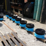 A long row of newly assembled blue hydraulic jacks, a type of essential bridge construction equipment.